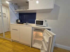 A compact kitchenette with a microwave, a sink, and a built-in refrigerator. - ORBI D2 "14 " Seaview quite studio (Batumi)