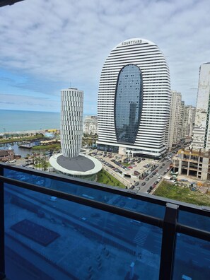 A modern building with a curved facade and a central atrium, surrounded by other high-rise buildings and a body of water. - ORBI cozy D Seaview (Batumi)