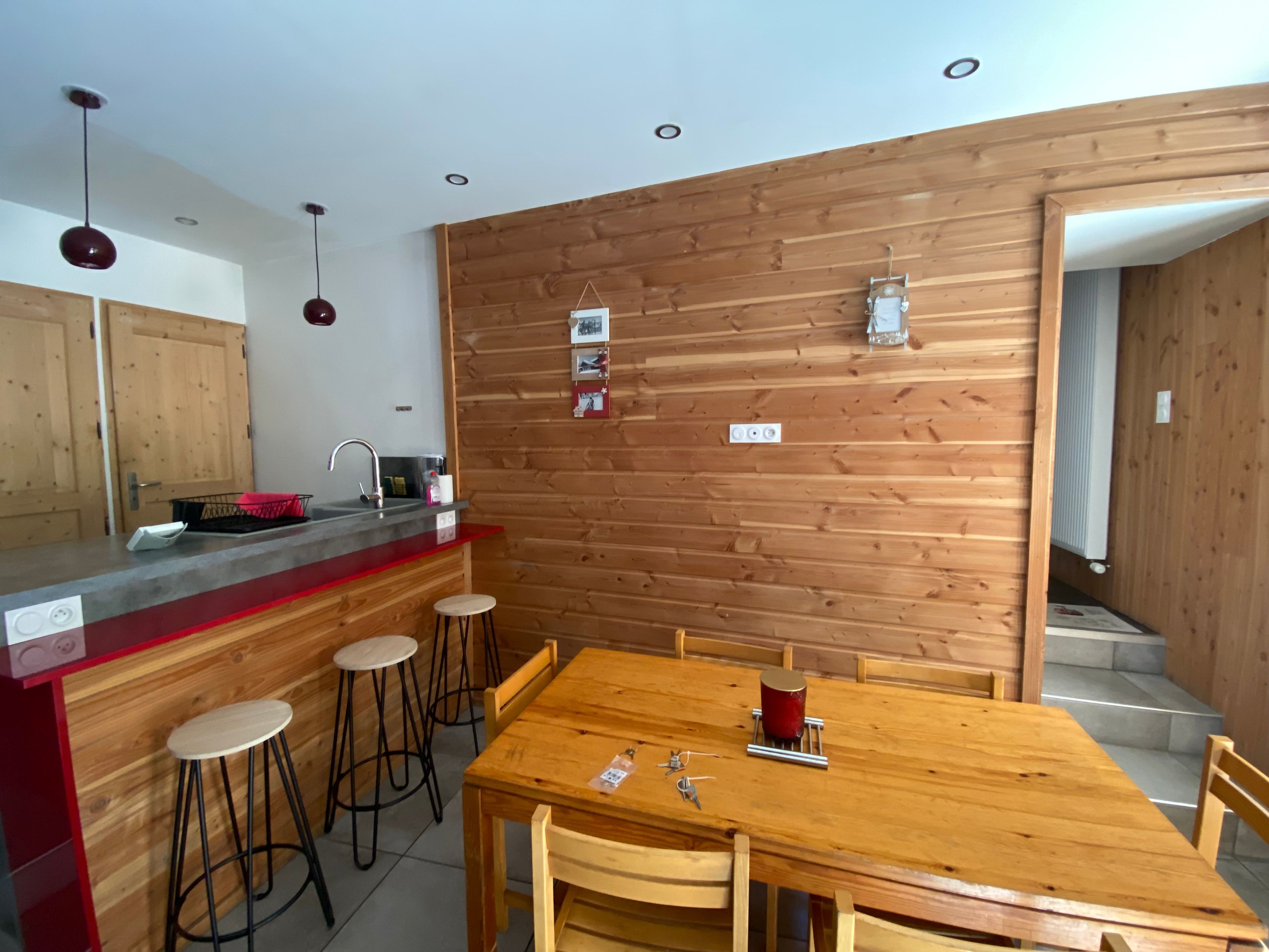 Eine moderne Küche mit einer Wand in Holzoptik, einer Bar und einem Esstisch mit Barhocker.