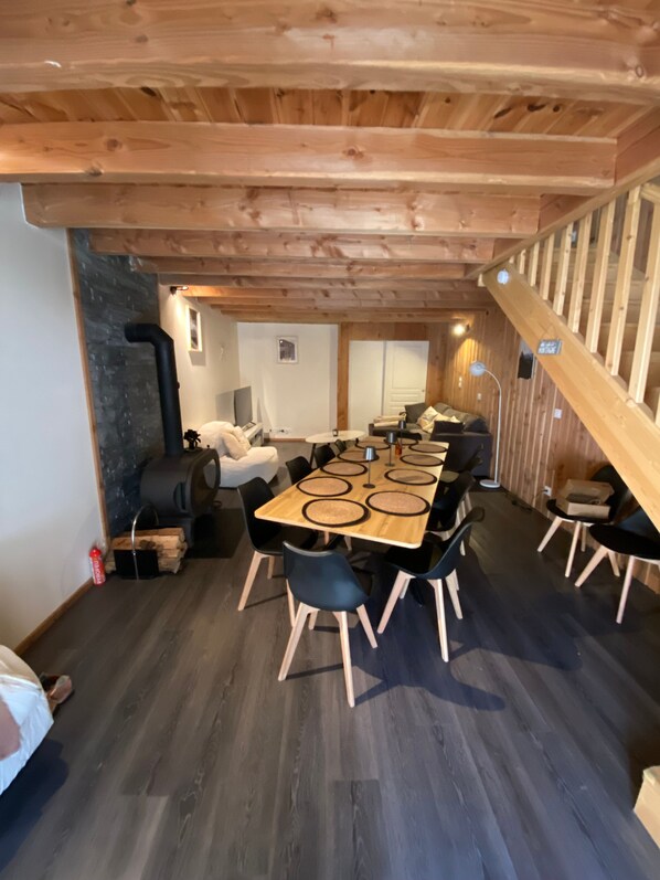 Un interior de madera con una mesa de comedor, sillas, un sofá y una escalera.