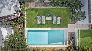 Ein rechteckiger Pool, umgeben von einer Rasenfläche mit Liegestühlen.