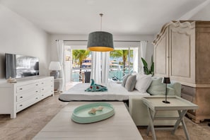 A modern bedroom with a bed, bedside table, and a view of the pool area. - Ground-Floor Corner 1BR, Sleeps 4 · Apt 23 Ocean Breeze (Kralendijk)