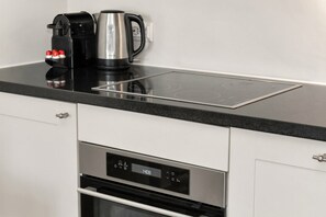 Een keuken met een geïntegreerde inductiekookplaat, een koffiezetapparaat en een bedieningspaneel voor de digitale oven.