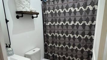 A small bathroom with a toilet, a sink, a towel rack, and a shower curtain.