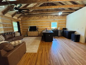 Ein Holzhaus-Interieur mit Wohnzimmer, Küche und Deckenventilator.