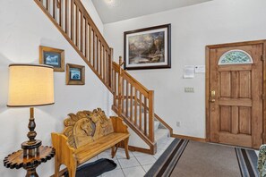 A staircase with wooden railings, a bench, a lamp, and a door with a window. - Spacious 3 Bedroom, 2 Full Bath with Deck, Private Hot Tub and Mountain Views (Blue River)