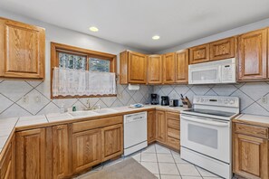 A kitchen with wooden cabinets, a microwave, an oven, and a dishwasher. - Spacious 3 Bedroom, 2 Full Bath with Deck, Private Hot Tub and Mountain Views (Blue River)