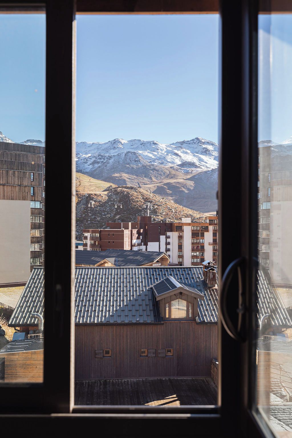 A view through a window of a building with a mountainous landscape in the background.