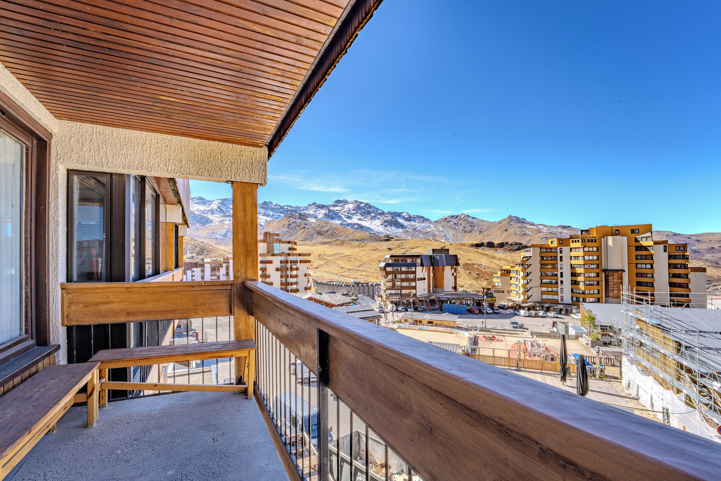 A balcony with a view of a mountainous landscape and a hotel building in the background.