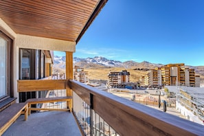 Un balcón con vistas a un paisaje montañoso y un edificio de hotel al fondo.