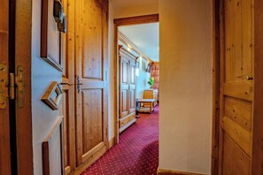 A wooden hallway with a red carpet, wooden doors, and a small table with chairs. - Glaciers (Les Belleville)