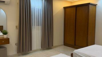 A bedroom with two beds, a wardrobe, a mirror, and an air conditioning unit.