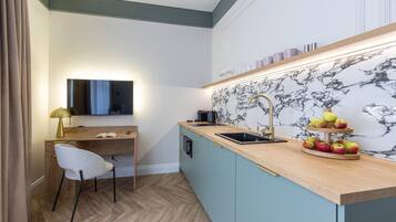A compact kitchenette with a wooden countertop, a sink, and a marble backsplash.