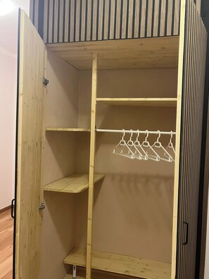 Armari de fusta amb portes obertes, que mostra prestatges i una barra penjant.