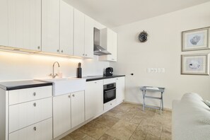 Una cocina moderna con armarios blancos, encimera negra, campana de acero inoxidable y una cafetera.