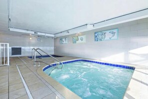 An indoor swimming pool with a tiled edge, a metal ladder, and artwork on the wall. - New Rental ~ Book Spring/Summer 2027! (Panama City Beach)