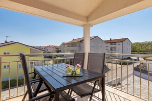 A balcony with a table and chairs, a view of neighboring buildings, and a clear sky. - New Listing (Čižići)