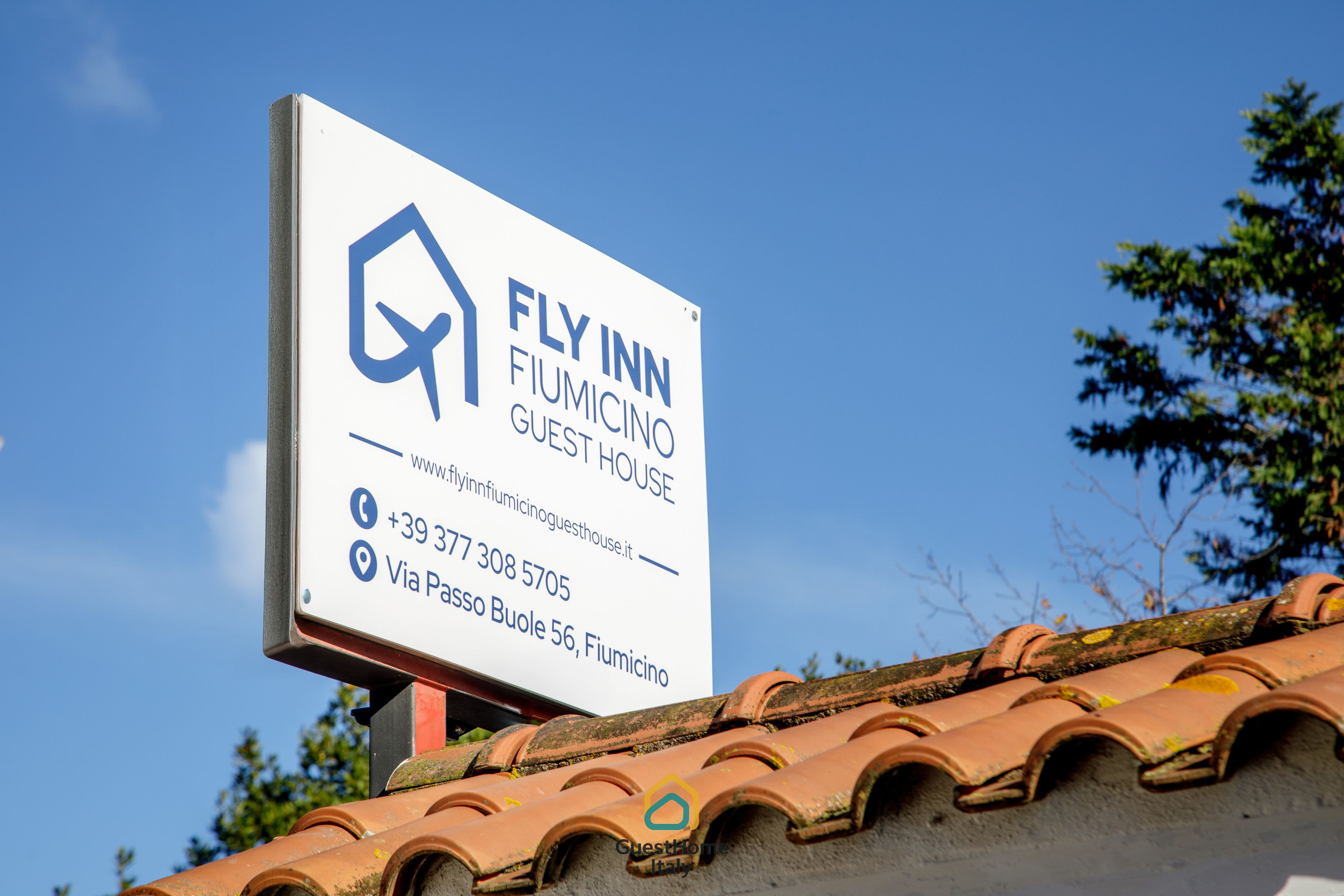 Een bordje voor Fly Inn Fiumicino Guest House met contactgegevens en adres.