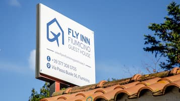 Señal de Fly Inn Fiumicino Guest House con información de contacto y dirección.