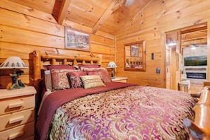 A wooden cabin bedroom with a bed, nightstands, and a fireplace. - Bearly Behavin - Smart Cabin, Hot Tub & Fire Pit (Sevierville)