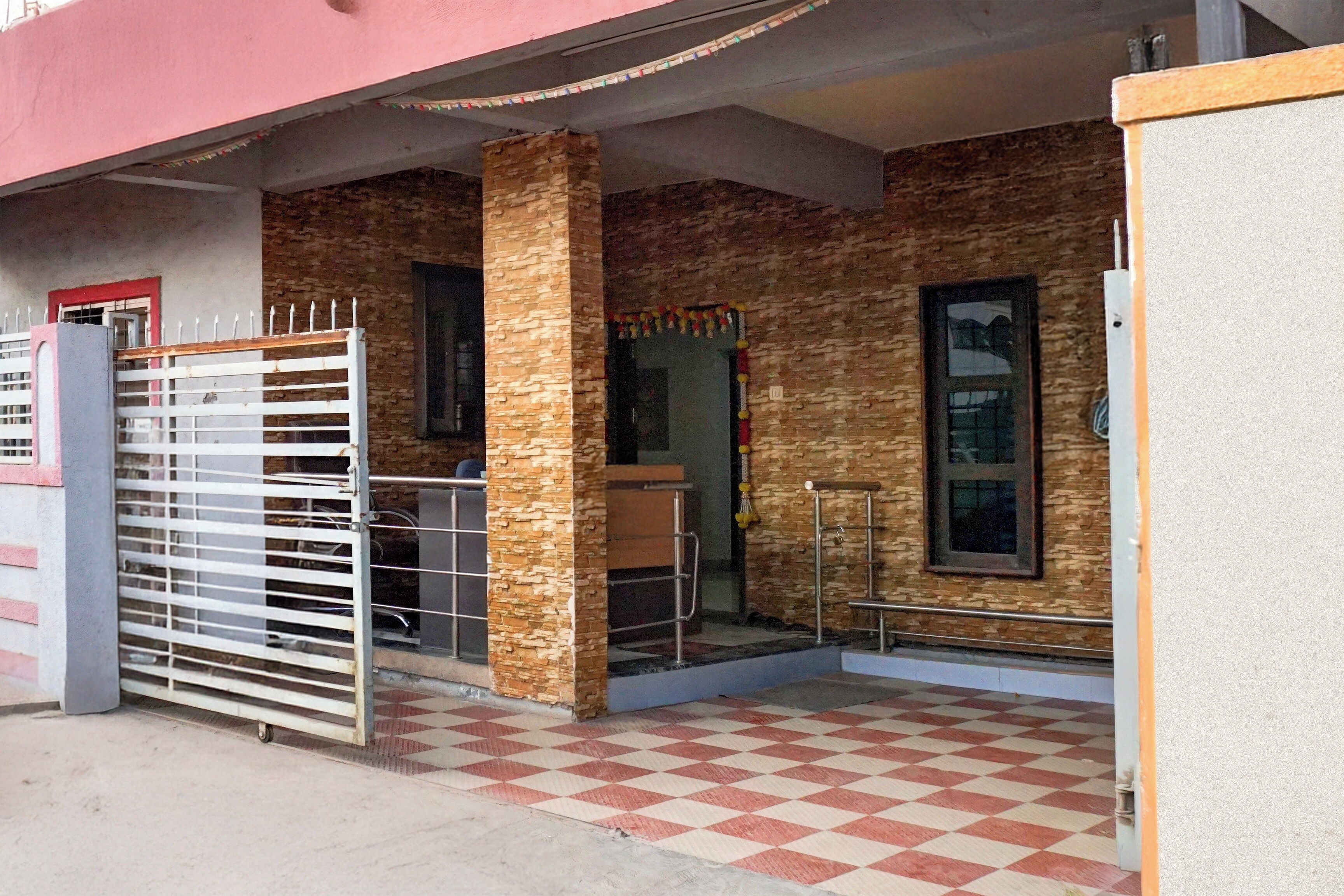 A building entrance with a gated driveway, a checkered floor, and a stone-textured wall.