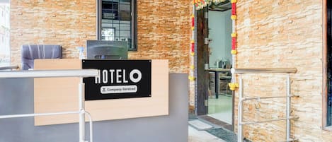 Ein Hotelrezeptionstresen mit einem Schild, das anzeigt, dass er betrieblich genutzt wird. Über dem Tresen befindet sich ein Fenster und rechts eine Tür.