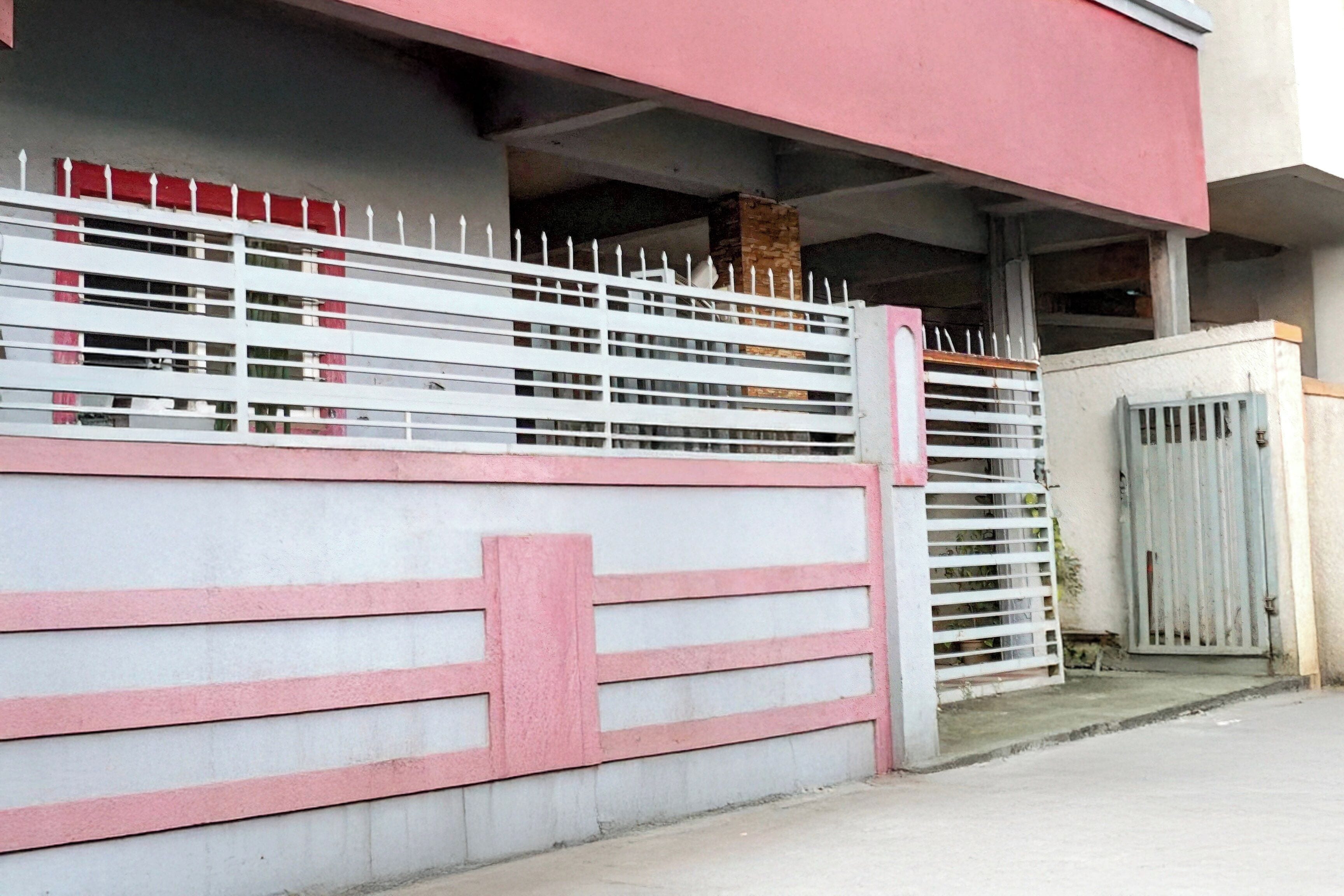 A gated property with a white and pink fence, a concrete wall, and a metal gate.