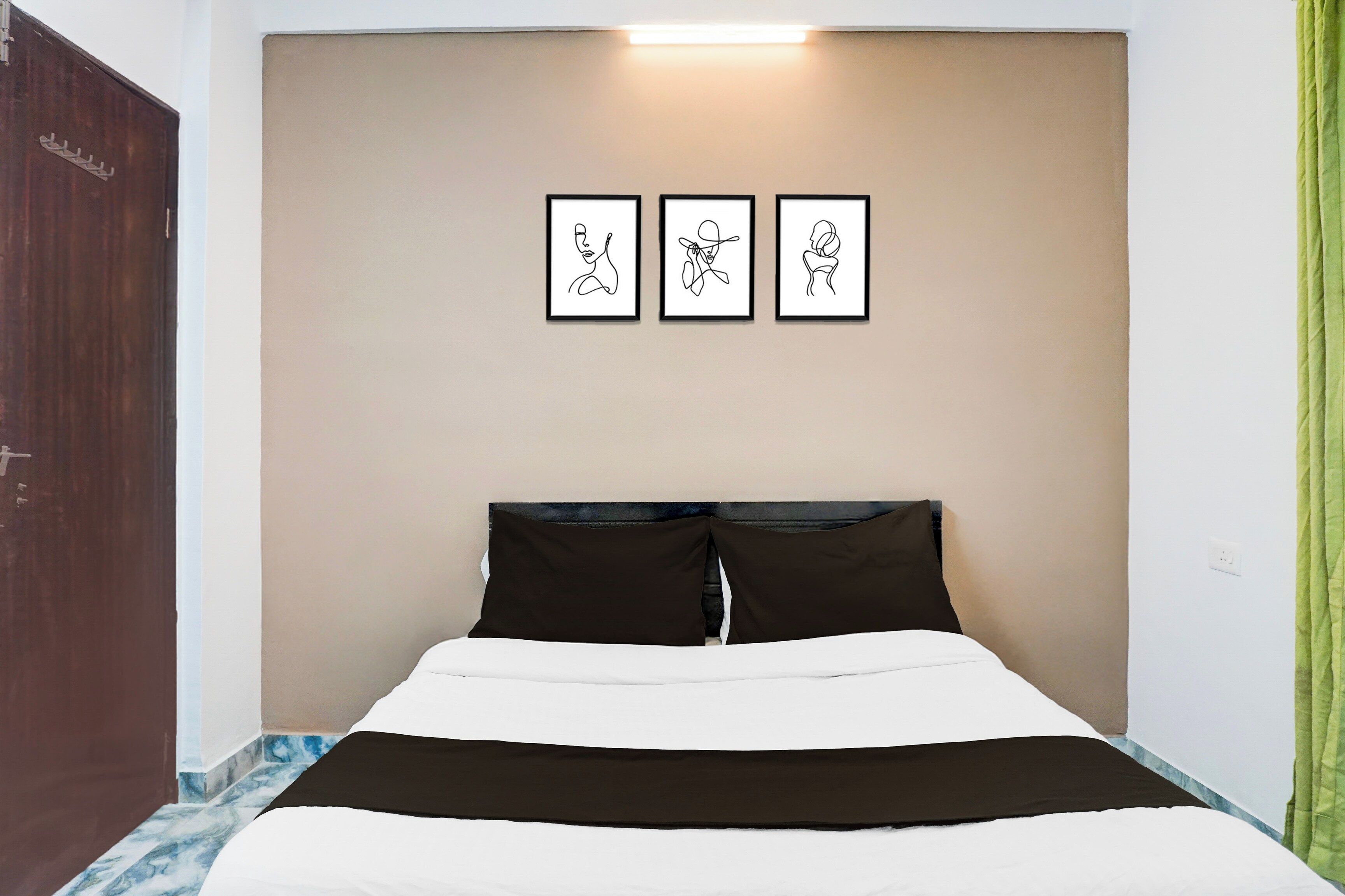 A bedroom with a bed, a headboard, and three framed artworks on the wall.