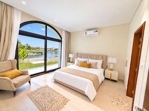 A hotel room with a large window, a bed, a sofa, and a view of a body of water.