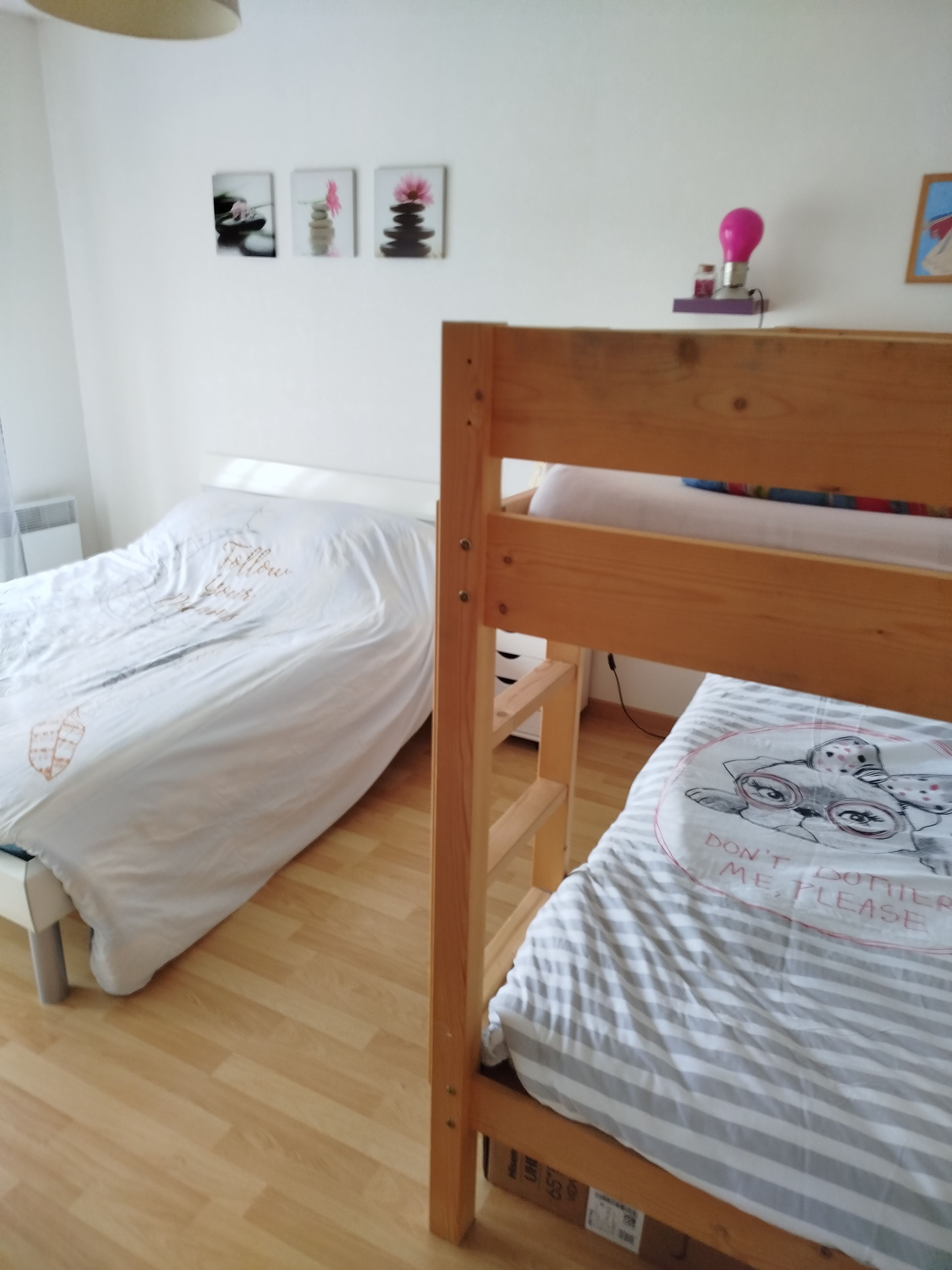 Ein Schlafzimmer mit zwei Etagenbetten, einem Nachttisch mit Lampe und einer Wand mit gerahmten Bildern.