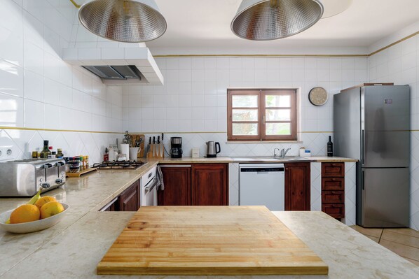 Eine moderne Küche mit weißen Fliesen, Holzschränken, einem Edelstahl-Kühlschrank und einer Holzarbeitsplatte.