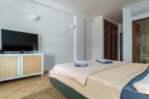 Ein Schlafzimmer mit einem Bett, einem Fernseher auf einer Kommode und einer Badezimmertür.