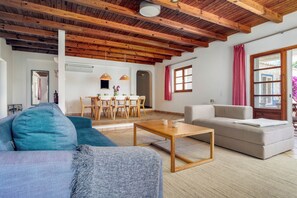 Ein geräumiges Wohnzimmer mit Holzboden, einer Couch, einem Couchtisch und einem Essbereich mit Stühlen und einem Tisch.