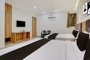Une chambre d’hôtel avec deux lits, une télévision, un ventilateur de plafond, un appareil de climatisation et une fenêtre avec des rideaux.