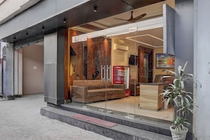 Entrada d'hotel amb una porta de vidre, un sofà a l'interior i un refrigerador de Coca-Cola.