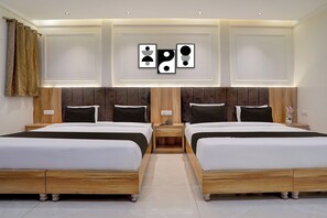 A hotel room with two beds, a wooden headboard, a nightstand, and a wall with framed artwork. - Townhouse by OYO Ram Talai Crossway (Amritsar)