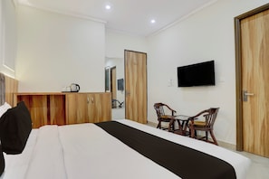 Une chambre d’hôtel comprenant un lit, un bureau, deux chaises, une télévision et une armoire.
