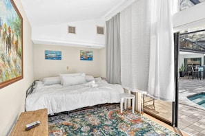 A hotel room with a bed, a small table, a colorful rug, and a view of a swimming pool. - Oak Haven Retreat - Pool, Hot Tub & Fire Pit (Brandon)