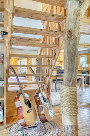 A rustic interior with exposed wooden beams, a staircase, and a dining area with a table and chairs. -  Large, Treehouse cottage, sleeps 15, 10 min from Ski-Wentworth, Dog Friendly (Westchester Station)