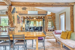 A rustic wooden interior with a dining area, a sofa, and a staircase.