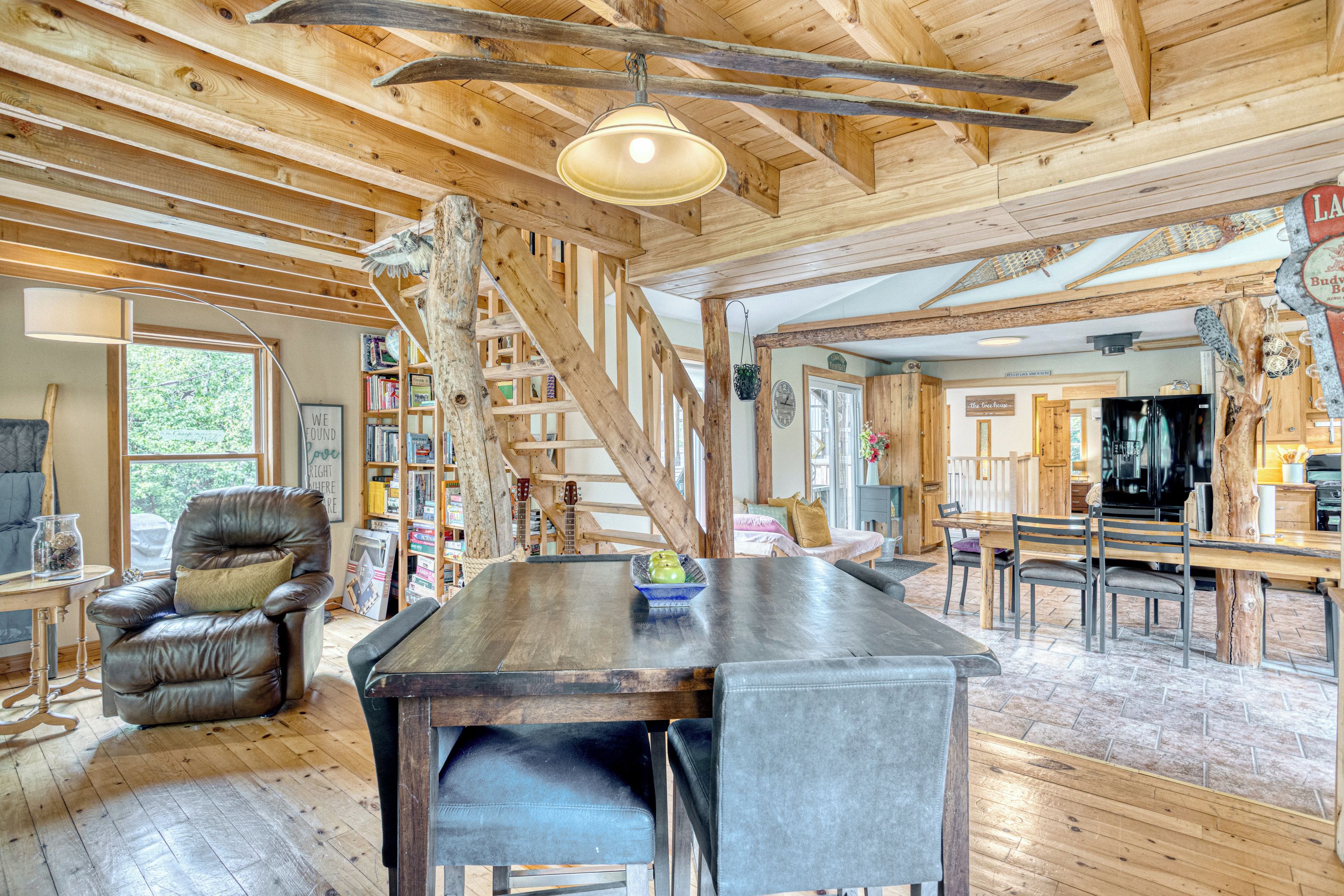 Une pièce spacieuse avec un plafond en bois, une table à manger avec des chaises, un fauteuil en cuir et une bibliothèque.