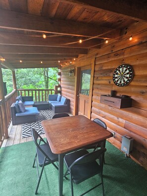 Eine Holzhütte mit einer Terrasse, einem Dartspiel und Gartenmöbeln.