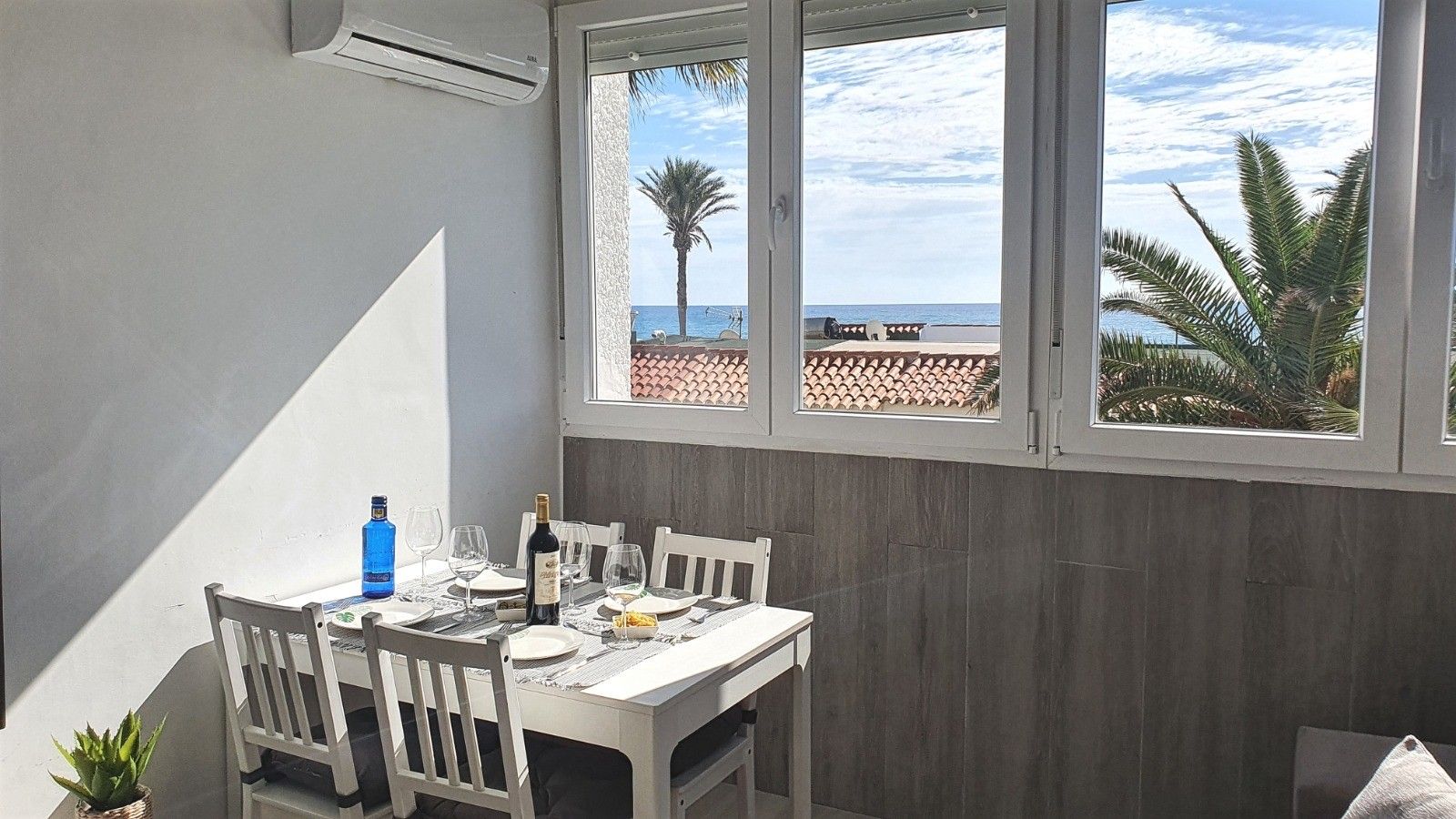 Un coin repas avec une table dressée pour deux personnes, une bouteille d’eau et des verres à vin.