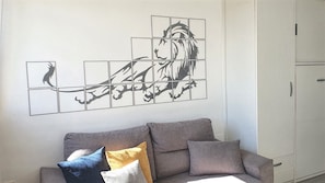 Una sala de estar con un sofá gris, una obra de arte en la pared y un mueble blanco.