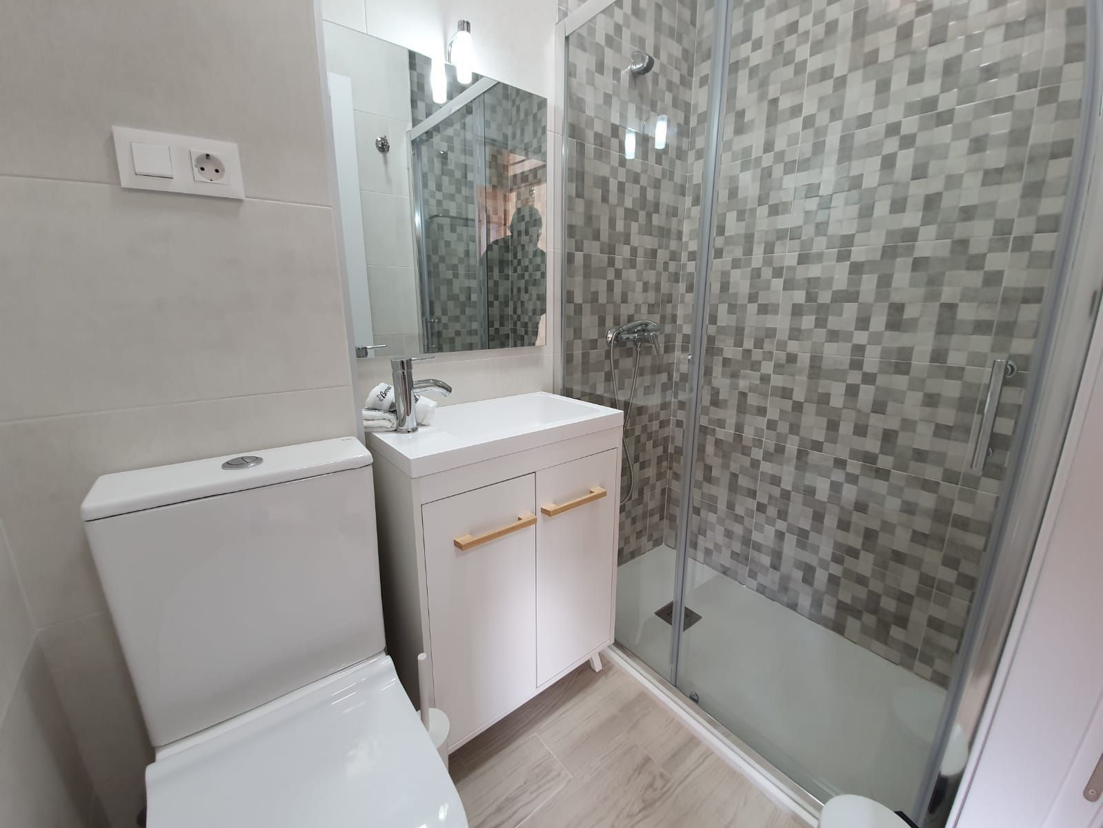 Une salle de bain moderne équipée de toilettes, d’un lavabo et d’une douche à parois de verre.