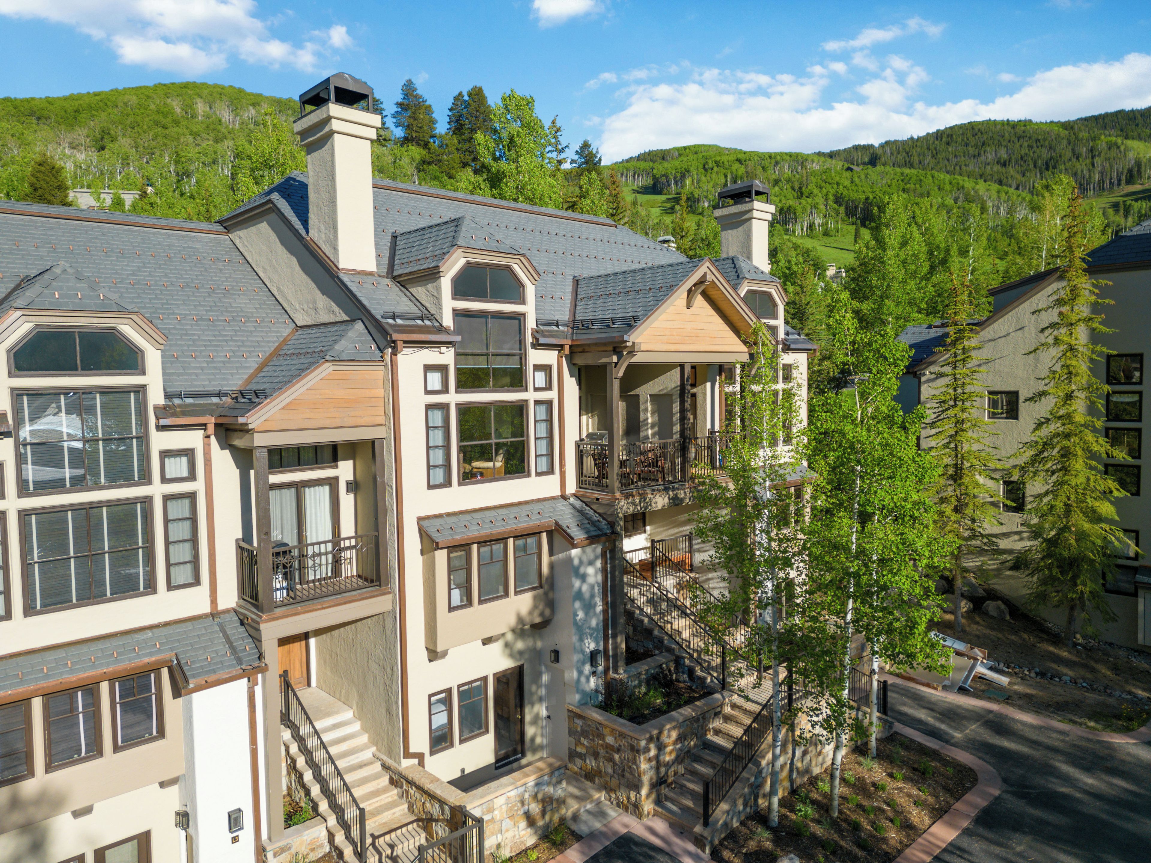 A multi-story residential building with a prominent staircase, large windows, and a balcony.