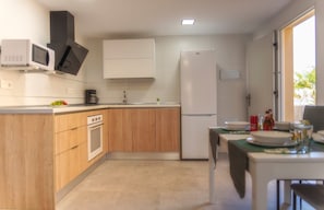 Una cucina compatta con microonde, fornello, lavello e frigorifero.