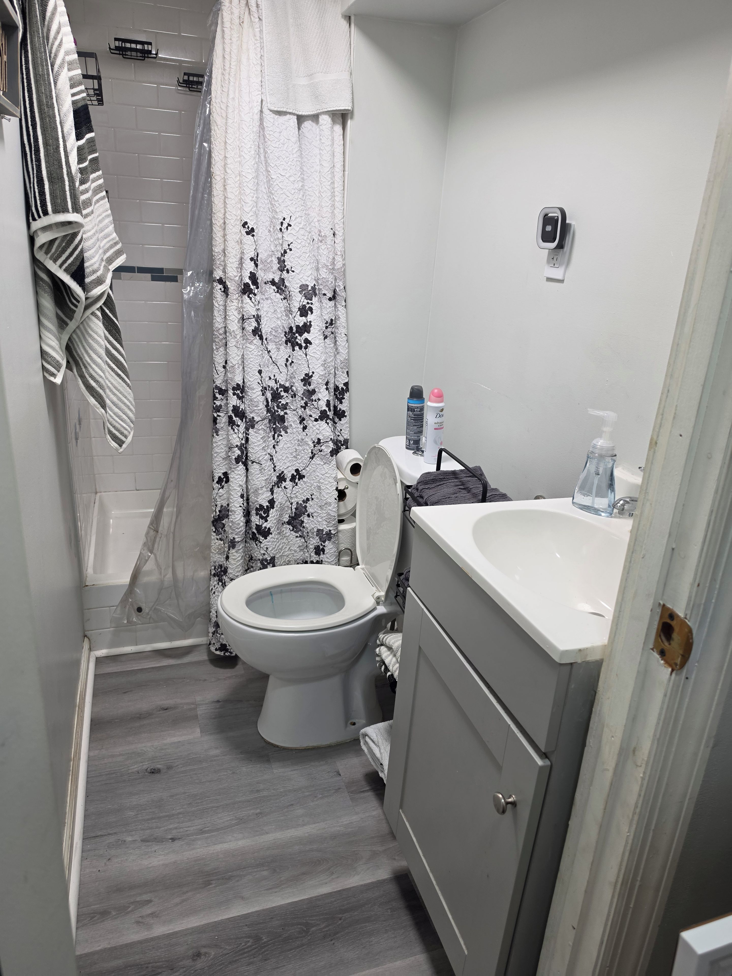 A bathroom with a toilet, sink, shower, and a towel rack.