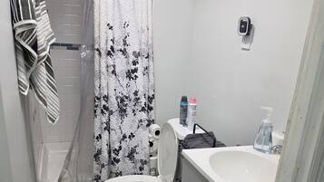A bathroom with a toilet, sink, shower, and a towel rack.