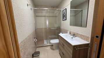 A bathroom with a shower, toilet, and sink.